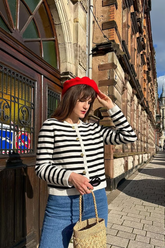 a lady in a black striped cardigan and a pair of blue jens